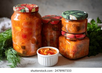 Pickled vegetable salad in a glass jar on a gray background. Close-up - Powered by Shutterstock