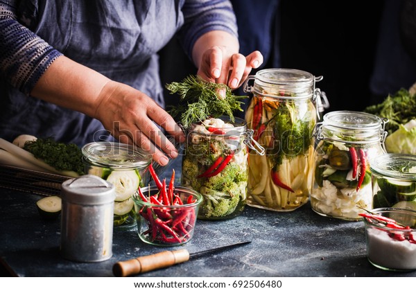 Pickled vegetables in jars displayed on table\
cauliflower broccoli bean cucumber green tomatoes fermented process\
glass jars variety copy\
space