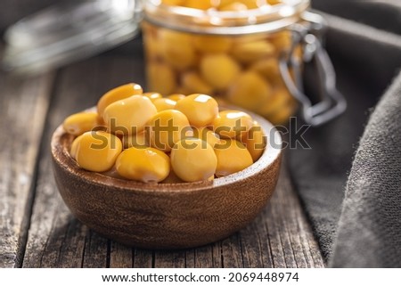 Pickled yellow Lupin Beans in bowl on wooden table.