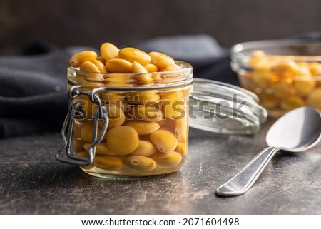 Pickled yellow Lupin Beans in jar on kitchen table.