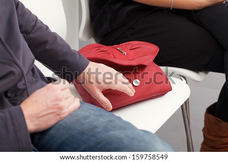 The pickpocket is going to steal the woman's red bag