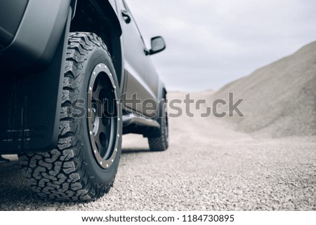 Pickup car are stopped on a dirt road. Off-road truck car wheels disassembly protection. Tire bad lock protection on the car wheel. Gravel road and space for a text