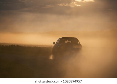 Pickup truck car in motion at the country road with clouds of dust. SUV car going fast on the dirt road at the sunset.