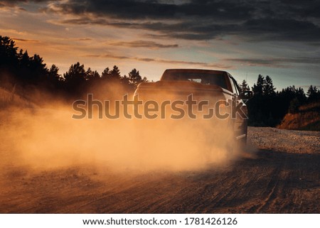 Pickup truck car in motion on a country road with clouds of dust. SUV car go fast on the rural road. Crossover at the desert