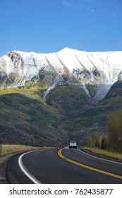 Pickup Truck On The Highway Below Mountains With Freshly Fallen Snow, Near Telluride, Colorado