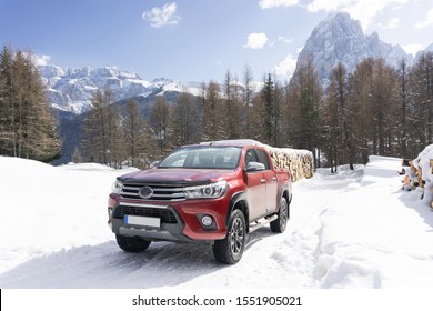 
Pickup truck on road, Beautiful winter road under snow mountains Dolomites, Italy. Shiny red truck measuring the depth of the snow