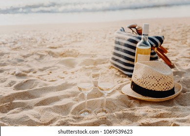 Picnic background with bag, grape and white wine on the beach by blue sea