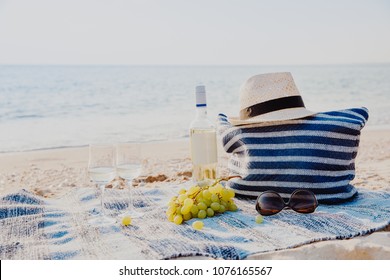 Picnic background with bag, grape and white wine on the beach by blue sea