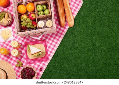 Picnic basket, different snacks and juice on green grass outdoors, top view. Space for text - Powered by Shutterstock