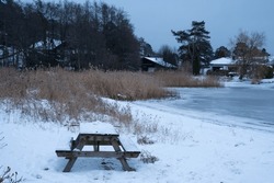 A Picnic Bench At The Beach In Sandefjord, Norway, Covered In Snow During Winter.