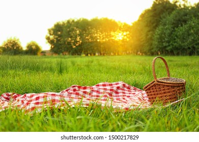 Picnic blanket and basket on grass in park