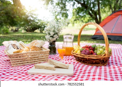 picnic bread croissant basket with fruit on  red white cloth and vase flower with jar of orange juice - Powered by Shutterstock