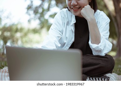 Picnic Concept A Girl With Short Hair Writing On Her IPad Sitting On A Map Surrounded By Trees.