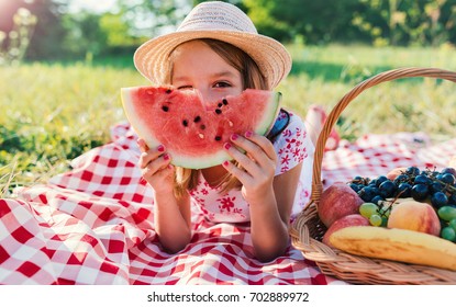 Picnic. Cute little girl eating watermelon and enjoying picnic in the park. Nature, lifestyle - Powered by Shutterstock