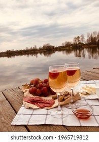 Picnic during Under dramatic storm sky with wine, grapes and cheese.