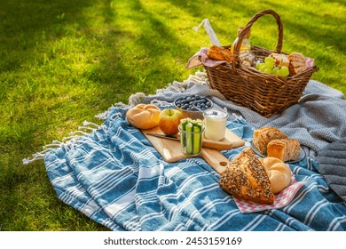 Picnic duvet and basket with different food, fruits, orange juice., yogurt and bread on green grass - Powered by Shutterstock