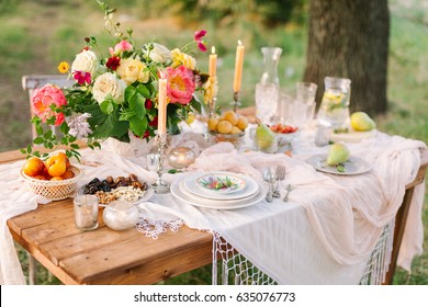 Picnic, Food, Summer, Festive Concept - Beautiful Table Setting At The Green Lawn With Tree, Colorful Summer Bouquet Of Peony And Roses, Openwork White Tablecloth, Lemonade, Glasses, Fruit.