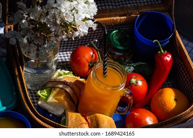 Picnic At Home. Picnic Indoor Concept. Fruits, Juice, Sandwiches And Flowers. Picnic Bag.