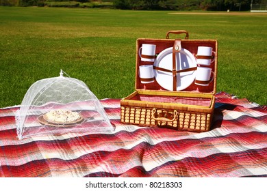 a picnic lunch outdoors in a nice field or park on sunny spring or summer day. picnic includes sandwich, chips, pie, drinks, a blanket and a baseball and glove with a blue sky and green grass. - Powered by Shutterstock