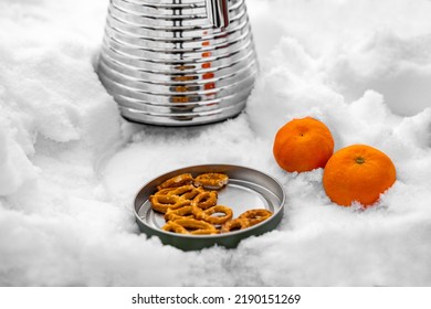 Picnic Lunch Snack On Table Covered With Snow Outside On Winter Day. Valentine's Date, Christmas Or New Year's Event With Salty Crackers, Two Mandarines Or Oranges And Metallic Termos With Warm