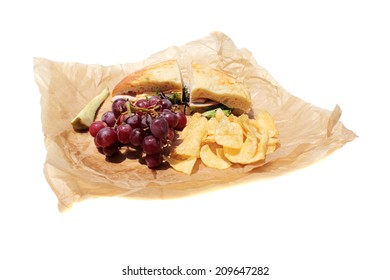 A Picnic Lunch With A Turkey And Cheese Sandwich On Cheese Bread, Chips, Red Grapes And A Dill Pickle Slice Wrapped In Deli Paper, Isolated On White. Deli Sandwiches Are A Favorite For Picnics 