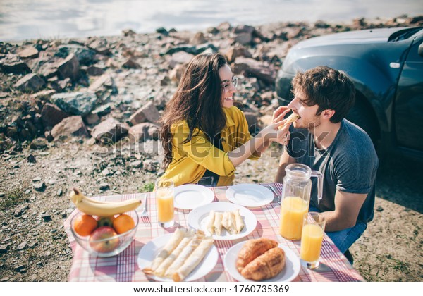 Picnic near the water. Happy family\
on a road trip in their car. Man and woman are traveling by the sea\
or the ocean or the river. Summer ride by\
automobile.