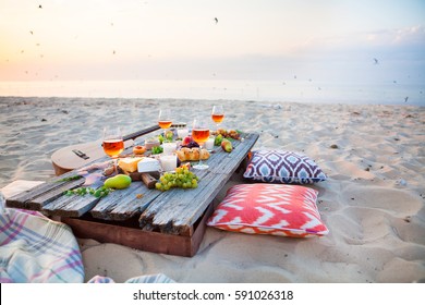 Picnic on the beach at sunset in the style of boho, food and drink conception