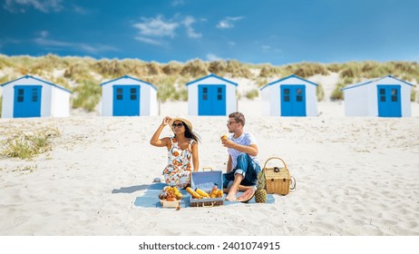 Picnic on the beach Texel Netherlands, couple of men and woman having a picnic on the coast of Texel with white sand and a colorful withe and blue house in Holland - Powered by Shutterstock