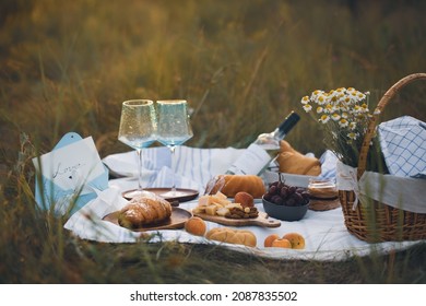 A picnic on the grass with wine and croissants.breakfast with a croissant.French breakfast. Food on the street.Croissants in nature. Romantic breakfast.Beautiful breakfast with champagne.Dinner.Summer