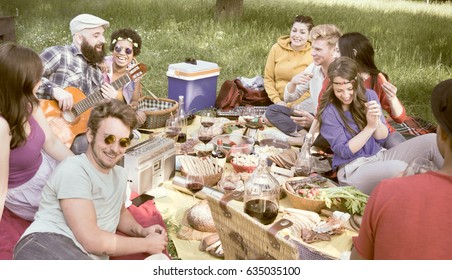 Picnic At Park. Diverse Friends Having Fun Drinking Wine And Enjoying Food Playing Guitar Outdoors Sitting On Meadow. Concept Of Diversity, College Students Fun Leisure And Easy Hipster Lifestyle. 