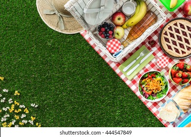 Picnic at the park on the grass: tablecloth, basket, healthy food and accessories, top view - Powered by Shutterstock