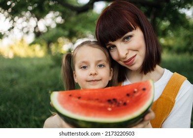 Picnic In Summer Park. Close Up Portrait Of Single Mom With Little Daughter Is Engaged In Eating Watermelon Resting Outdoor.