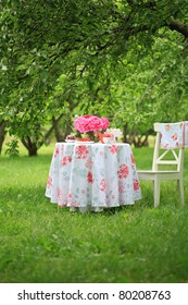 Picnic table with beautiful bouquet of pink peony on it and chair in beautiful park
