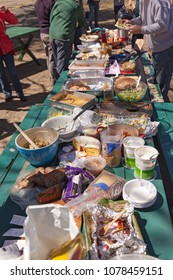 A Picnic Table Full Of Food At An Outdoor Picnic Potluck Community Lunch.