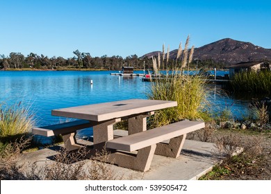 Picnic table at Lake Murray in San Diego, California with boat rental dock and Cowles Mountain in the background, 