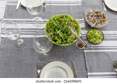 A Picnic Table With A Large Bowl Of Tossed Garden Salad And Plates