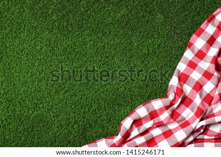 Picnic tablecloth on grass, top view. Space for text