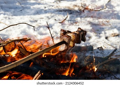 Picnic in winter. Cooking bacon on a fire in the winter forest during a hike, highting. The concept of winter recreation, camping, tourism in winter.