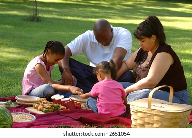 Picnicking family saying grace before their meal.