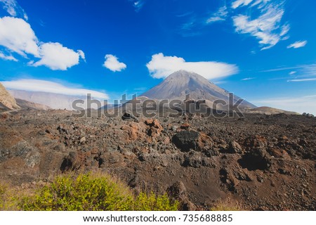 Pico do Fogo, volcano on the island of Fogo on Cabo Verde islands, with some grass and rocks in the foreground.