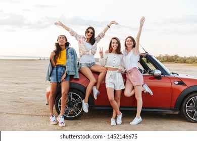 Picture Of Amazing Smiling Optimistic Young Cheery Women Friends Posing Near Car Outdoors At The Beach.