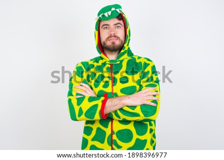 Picture of angry Young caucasian man wearing a pajama standing against white background looking camera.