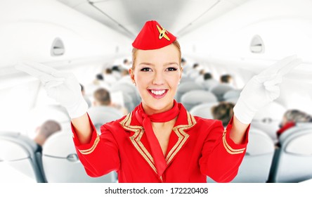 A Picture Of An Attractive Stewardess Showing Emergency Exits In A Plane