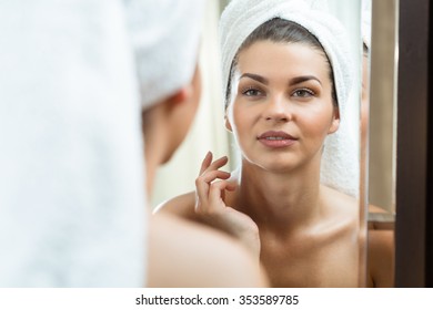 Picture of beautiful brunette looking at herself in the mirror