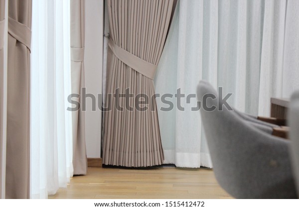Picture of beautiful neatly tie-back beige\
fabric curtain drapes over lighten white sheers in the cozy\
contemporary room. Resident, Elegant, Charming, Interior design,\
Protecting sun light,\
Expensive.
