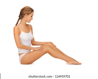 Bild einer schönen Frau in Baumwollunterwäsche, die ihre Beine berührt
