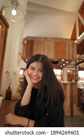 
A picture of a beautiful young Asian woman smiling looking at the camera.