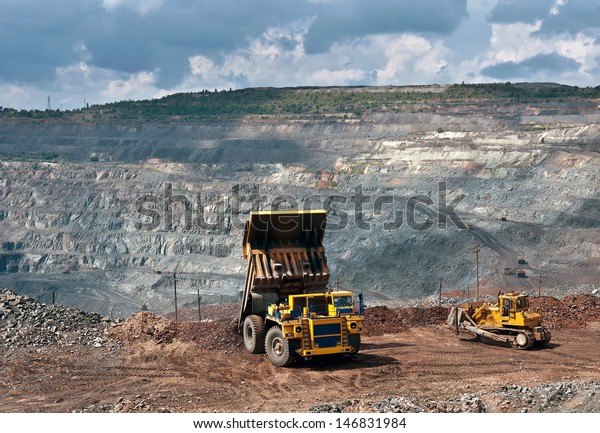A picture of a big yellow mining truck and bulldozer\
at work site