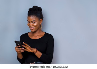 Picture Of A Black African Girl On Black Long Sleeves Smiling While Using Her Phone 