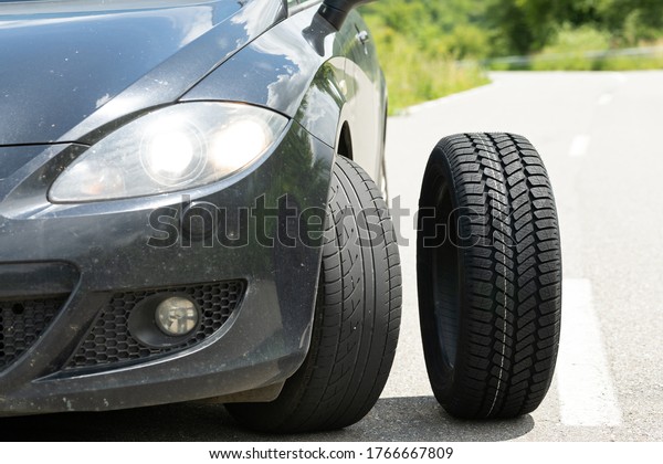 Picture of black car\'s brand new tyre on the road on\
a summer day